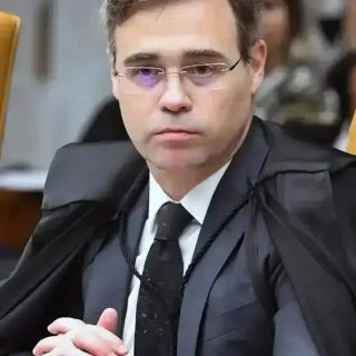 Supremo do Tribunal de Justiça, juiz em sessão, julgando processo, com expressão séria, usando toga preta e gravata, em ambiente judicial formal, assinado na bancada de julgamento.