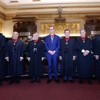 Juízes e autoridades em sessão do tribunal de justiça com decoração clássica e símbolos de poder jurídico.