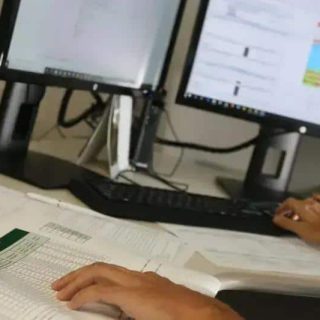 Relatório de análise jurídica sendo realizado em escritório de advocacia com computadores e documentos.