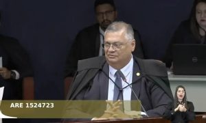 Advogado em tribunal durante sessão de julgamento de caso de direito, com outros profissionais ao fundo.