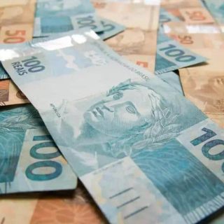 100 reais em cédulas de dinheiro brasileiro sobre fundo de notas de diversos valores, conceito de dinheiro, economia e finanças.