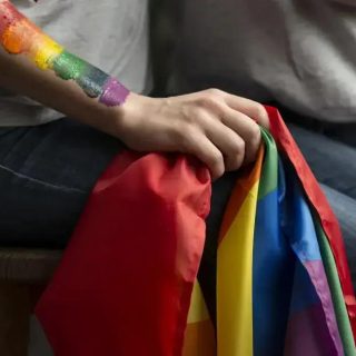 Organização LGBTQ+ com bandeira colorida e tinta na pele, refletindo temas de direitos e inclusão.