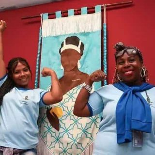 Mulheres profissionais do direito posicionando-se com força e coragem em frente a uma obra de arte que celebra o empoderamento feminino.