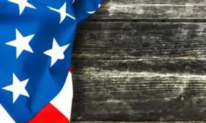 US flag draped on a weathered wooden surface, symbolizing patriotism, national identity, or American values. Ideal for content related to u.s. law, politics, or national news.