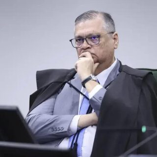Juiz de direito em tribunal, vestindo toga e gravata, analisando processo judicial com expressão pensativa e concentrada, representando o setor jurídico e o direito hoje notícias.