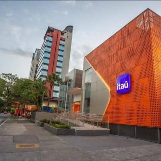 Banco Itaú na cidade com destaque para sua fachada moderna e fachada laranja vibrante, representando inovação e segurança nos serviços financeiros, no centro de uma área urbana movimentada.