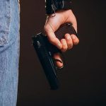 Arma de fogo sendo manuseada por uma pessoa, ilustrando temas de segurança e legislação policial no contexto do Direito Hoje Notícias.