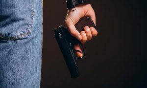 Arma de fogo sendo manuseada por uma pessoa, ilustrando temas de segurança e legislação policial no contexto do Direito Hoje Notícias.