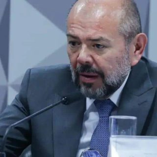 Advogado hablando durante conferência sobre direito e notícias jurídicas em ambiente formal.