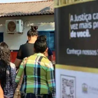 Aparelhos de ar-condicionado instalados em fachada de prédio acadêmico, com pessoas caminhando na rua, em ambiente urbano durante o dia, com atmosfera de rotina e atividades cotidianas ligadas ao direito e justiça.