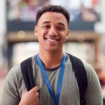 Estudante sorridente com mochila em ambiente acadêmico, representando direito, educação, estudantes e notícias de direito hoje.