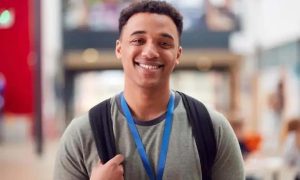 Estudante sorridente com mochila em ambiente acadêmico, representando direito, educação, estudantes e notícias de direito hoje.