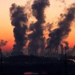 Poluição industrial com fumaça saindo de fábricas ao entardecer, impacto ambiental e questões jurídicas relacionadas à proteção do meio ambiente no Brasil.