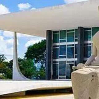 Estátua de mulher moderna sentada em frente ao edifício do Supremo Tribunal Federal em Brasília, representando justiça e direito no Brasil.