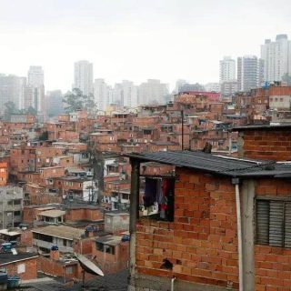 Favelas urbanas com prédios altos ao fundo, mostrando desigualdade social, moradia precária e desafios territoriais, tema destacado em notícias de direito e políticas públicas.