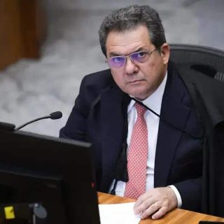 Analista judicial sentado em tribunal com traje formal e expressão séria, representando o tema de direito, jurisprudência e notícias jurídicas no Brasil.