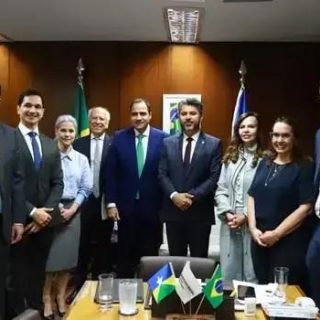 Reunião de profissionais do direito e autoridades com bandeiras do Brasil e do Estado, discutindo temas jurídicos relevantes e fortalecimento das instituições no contexto legal.