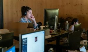 Operadora de atendimento ao cliente usando headset em ambiente de escritório com computadores e informações jurídicas, representando direitos e notícias jurídicas atuais.
