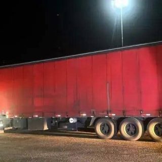 Transportadora de carga parada na estrada à noite, destacando a importância do transporte de cargas e segurança no trânsito.