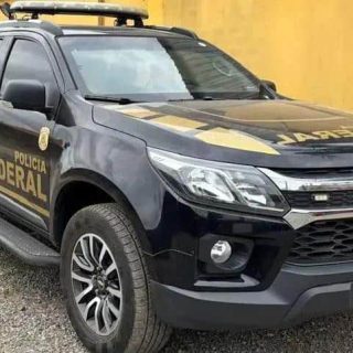 Polícia Federal Chevrolet S10 blindada com detalhes em verde e amarelo estacionada em frente a uma parede amarela, destacando operações de segurança e combate ao crime.