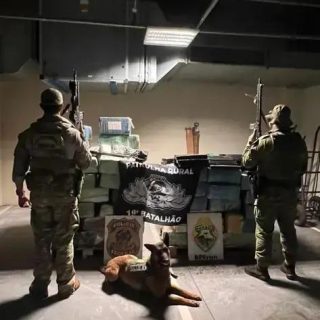 Armados policiais militares em operação com cão farejador em ambiente de garagem ou depósito, mostrando aparato policial e estratégia de combate ao crime, com foco na segurança e leis.