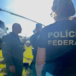 Polícia Federal atuando em investigação criminal na rua com equipe policial ao fundo.