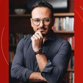 Advogado pensativo com óculos, usando camisa escura, em ambiente de biblioteca, representando notícias de direito, jurisprudência e atualidades jurídicas no portal Direito Hoje Notícias.