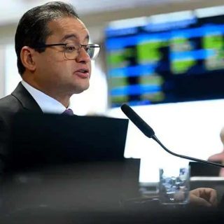 Direito Hoje Notícias - Advogado em audiência no tribunal com tela de votações ao fundo.