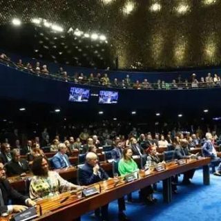 Salão de audiência do Congresso Nacional com parlamentares e autoridades em sessão legislativa, representando direito e políticas públicas no Brasil.