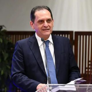 Direito Hoje Notícias, imagem de homem discursando em evento jurídico, com fundo de painéis de madeira, vestindo terno e gravata, representando notícias recentes e análises sobre direito e jurisprudência.