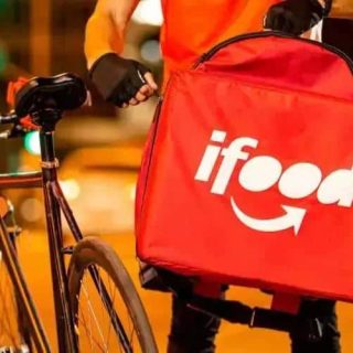 Entrega de comida rápida com bike, serviço de delivery do iFood, recorte urbano na noite, destaque para aplicativo de delivery de alimentos, transporte de pedidos de comida.