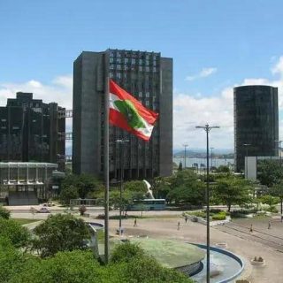 Bandeira do Pará em destaque na cidade de Belém, com edifícios modernos ao fundo e céu azul, representando o desenvolvimento e o crescimento econômico do estado.