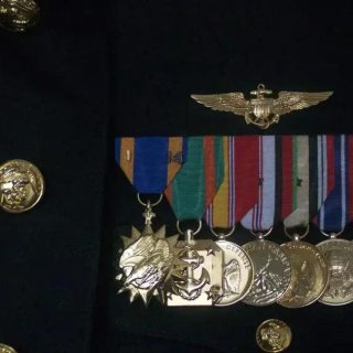 Medalhas militares e insígnia de alta patente com uniforme escuro, simbolizando honra, serviço e reconhecimento em direito e segurança pública.