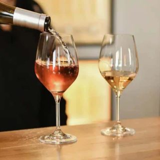 Bebida sendo servida em taça de vinho rosé, ambiente de bar, consumo de álcool, taças de vinho, Direito Hoje Notícias.