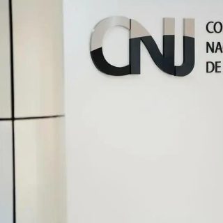 CNJ Conselho Nacional de Justiça logo na parede de uma sala de tribunal, representando o órgão que assegura a justiça e o estado de direito no Brasil.