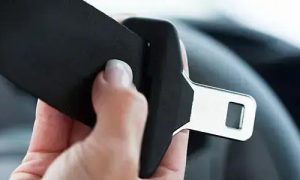 Cinto de segurança sendo afivelado no carro, foco em segurança de trânsito e legislação de trânsito.