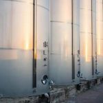 Tanques de armazenamento de líquidos metálicos em instalações industriais, representando segurança e regulamentação ambiental.