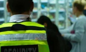 Homem de segurança em ambiente de loja ou supermercado, focado na proteção e segurança dos clientes, destacando a importância da segurança pública e privada.
