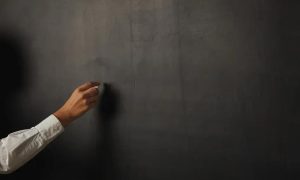 Fachada de quadro-negro com mão escrevendo com giz, símbolo de educação, escola ou aula, conceito de aprendizado e ensino, ambiente escolar, educação formal, sala de aula moderna, imagem representativa de ensino e formação profissional.